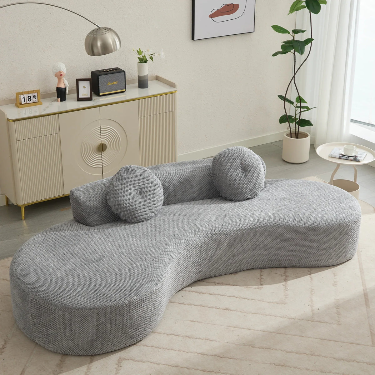A modern gray curved sofa with plush cushions and upholstered polyester fabric, comfortably seating three people.