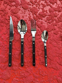 Close-up of modern ivory-handled forks and spoons from the Nordic flatware set resting on a textured fabric.