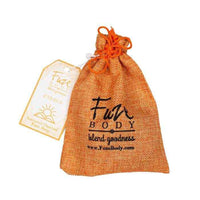 Facial soap bar next to various natural food ingredients including orange and ginger root.