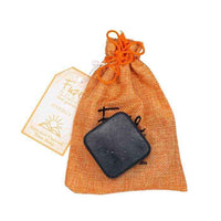 Energy Activated Charcoal Facial Soap with orange coin purse on white background.