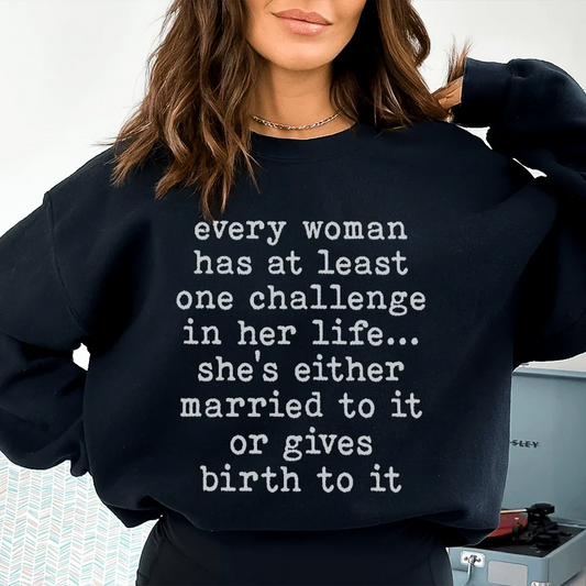 Black sweatshirt with white text 'Every Woman Has At Least One Challenge In Life' on front.