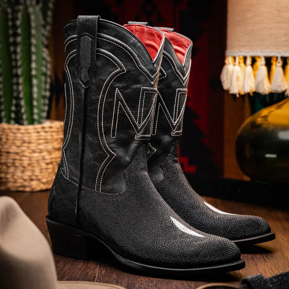 Lifestyle image of person wearing Georgia black stingray cowboy boots with jeans outdoors.