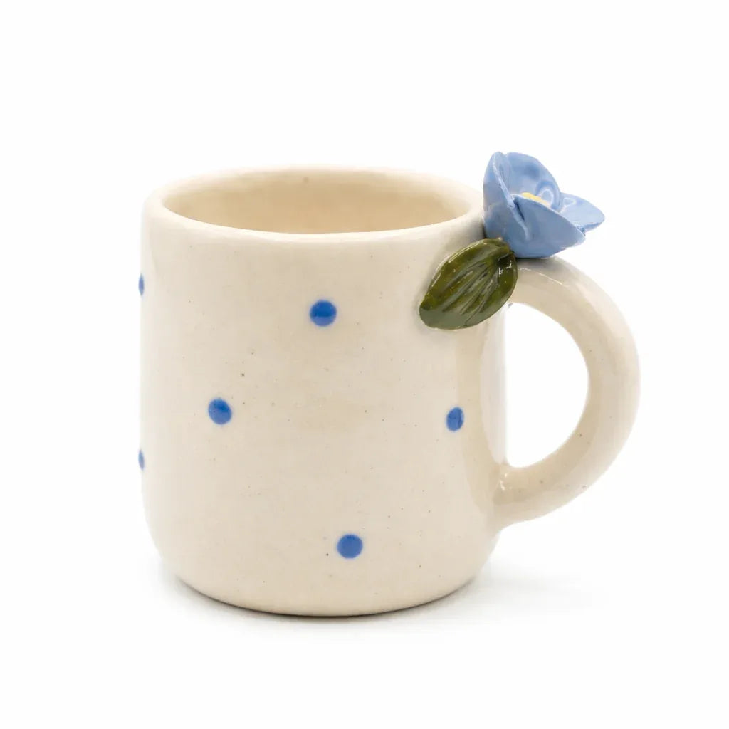 White mug with black polka dots and blue floral design, handcrafted ceramic coffee cup