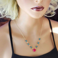 Elegant gold-filled necklace with interlinked turquoise and pink chalcedony gems on white background.