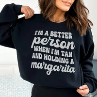 Black T-shirt with 'I'm A Better Person When I'm Tan And Holding A Margarita' printed in peach text.