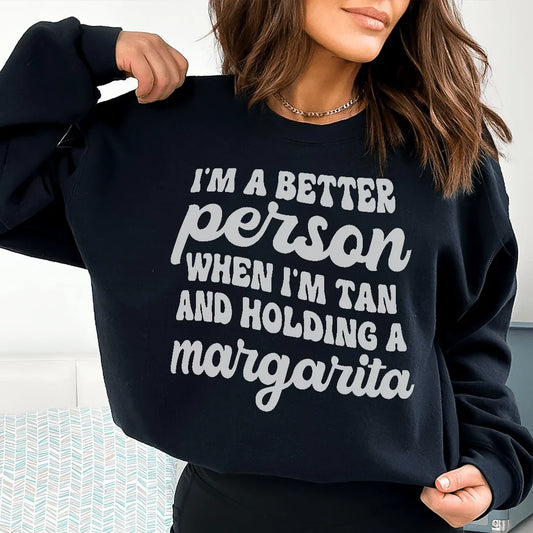Black T-shirt with 'I'm A Better Person When I'm Tan And Holding A Margarita' printed in peach text.