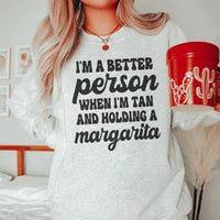Sport grey T-shirt featuring peach colored print saying 'I'm A Better Person When I'm Tan And Holding A Margarita'.