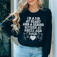 Black sweatshirt with white and peach lettering displaying 'I'm A Kid At Heart And A Senior Sitizen.'