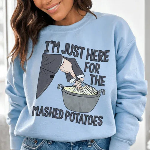 Close-up of light blue sweatshirt showing cozy fleece fabric and 'I'm Just Here For The Mashed Potatoes' text.