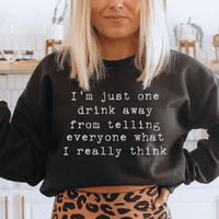 Close-up of peach sweatshirt showing fleece texture and 'I'm Just One Drink Away' printed text.
