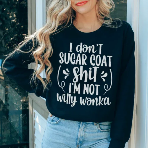 Close-up of black sweatshirt featuring white 'I'm Not Willy Wonka' text, flat lay view.