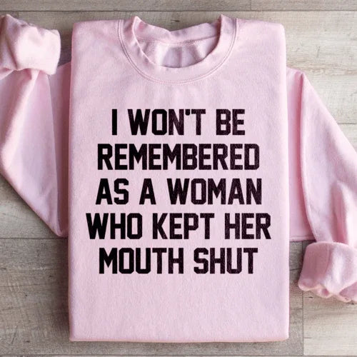 Light pink sweatshirt displaying the text 'I Won't Be Remembered As A Woman Who Kept Her Mouth Shut' in white letters.