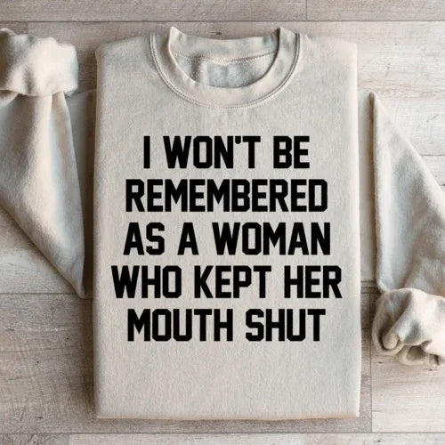 Sand-colored sweatshirt featuring the statement 'I Won't Be Remembered As A Woman Who Kept Her Mouth Shut' in white text.