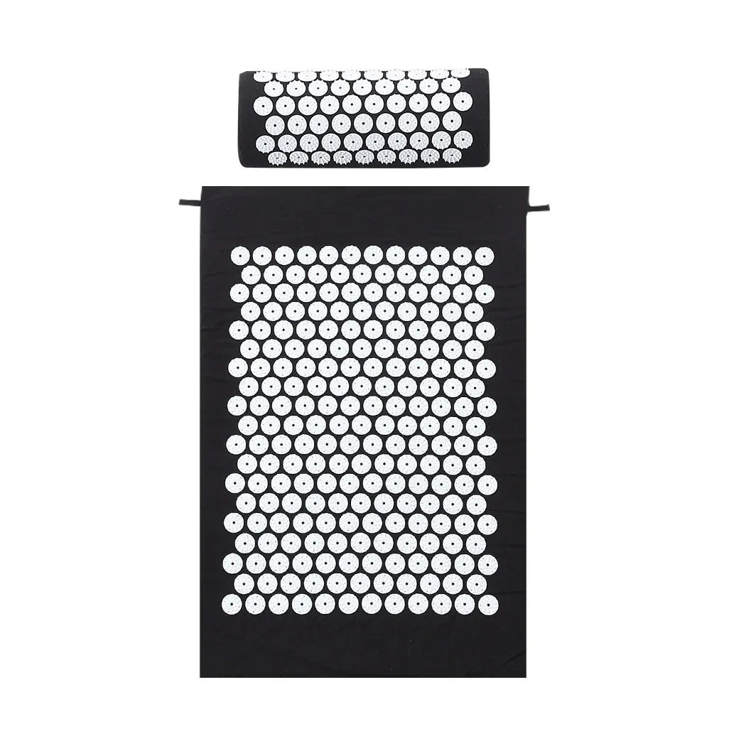 Black acupressure mat laid flat on floor, designed for sitting or lying