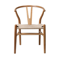Close-up of a wood dining chair showing the woven rattan seat and sleek wooden frame detail.