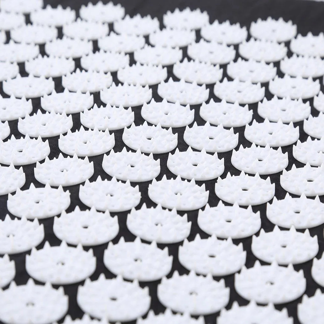 Woman relaxing while lying on black acupressure mat during pain and stress therapy