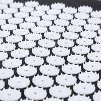 Woman relaxing while lying on black acupressure mat during pain and stress therapy