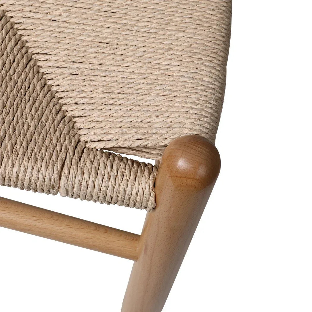 Wooden dining chair with rattan seat shown on a wooden floor with plain background.