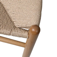Wooden dining chair with rattan seat shown on a wooden floor with plain background.