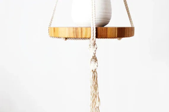 Close-up of intricate knots on a vintage-inspired macrame plant hanger holding a round wooden pot tray