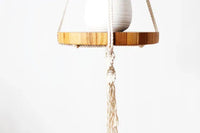Close-up of intricate knots on a vintage-inspired macrame plant hanger holding a round wooden pot tray