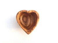 Heart-shaped mini dish holding small gold jewelry on a white surface.
