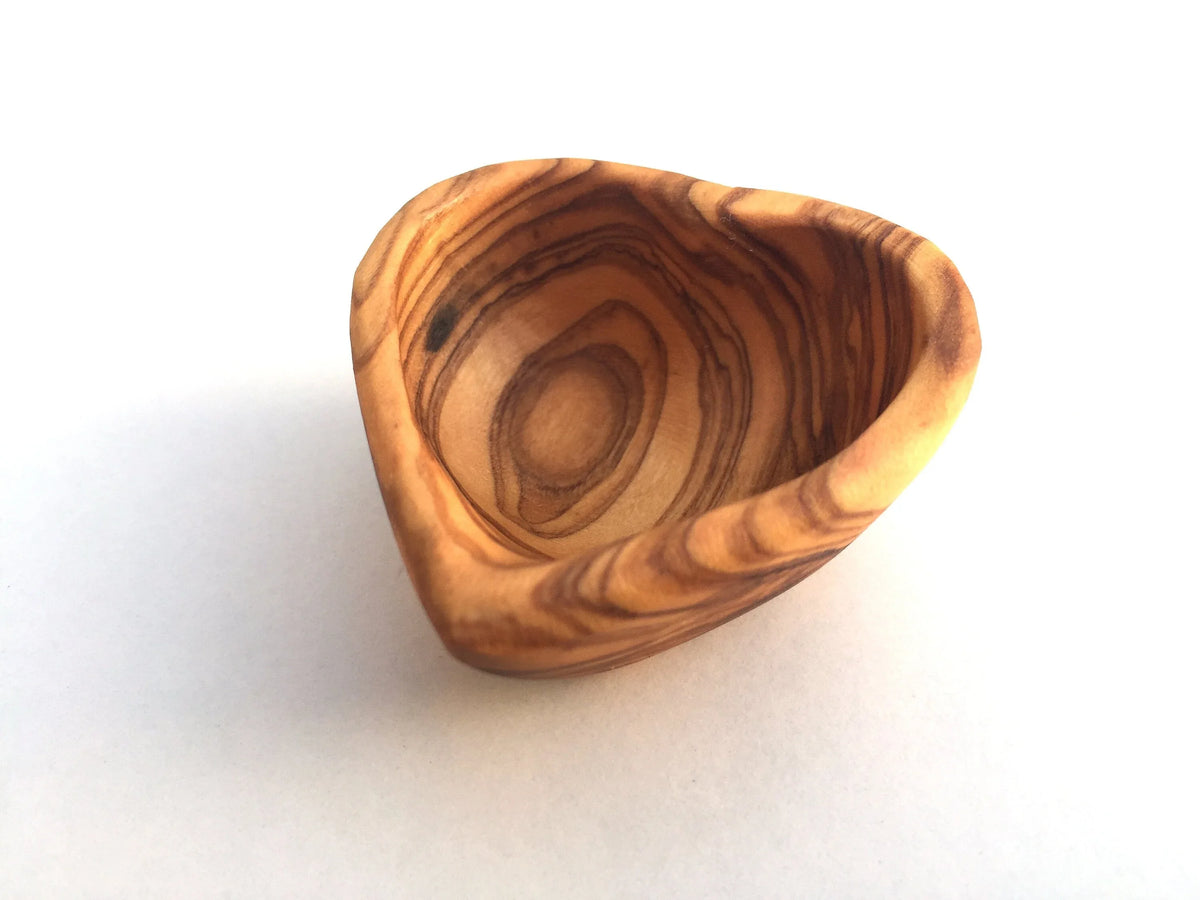 Empty ceramic heart-shaped mini bowl on a wooden table background.