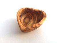 Empty ceramic heart-shaped mini bowl on a wooden table background.
