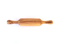 Mini rolling pin placed on a wooden cutting board alongside cookie dough and baking tools.