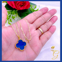Detailed view of gold cloverleaf pendant with blue accents highlighting intricate craftsmanship.