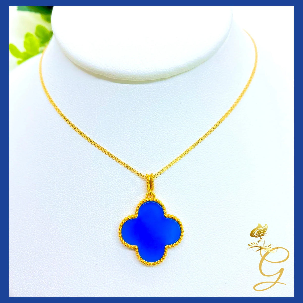 18K yellow gold cloverleaf necklace draped over a white surface showing chain length and pendant details.