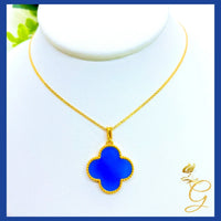 18K yellow gold cloverleaf necklace draped over a white surface showing chain length and pendant details.
