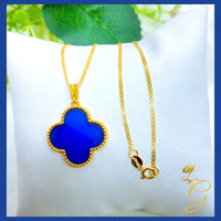 Model wearing the 18K gold cloverleaf necklace with blue detailing against a neutral background.