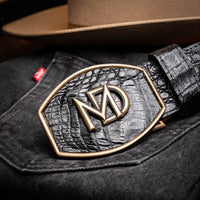Black caiman skin belt styled with dark denim in an outdoor setting