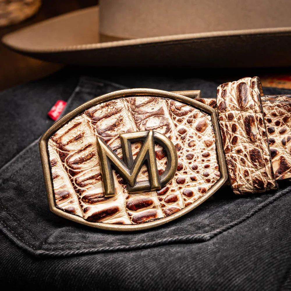 Close-up lifestyle view of belt featuring natural caiman scales and antique brass buckle on wearer.