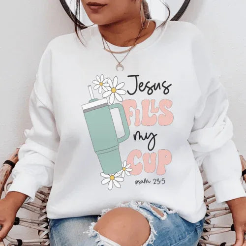 White sweatshirt featuring "Jesus Fills My Cup Psalm" text design in black lettering.