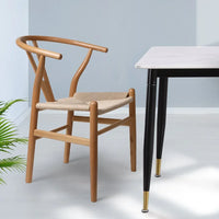 Bright dining room setup with wooden rattan seat chairs around a wooden dining table.