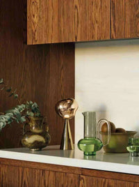 Portable rechargeable table lamp with a soft glowing light on a tan bedside surface.