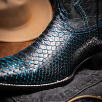 Man walking in Missouri black and blue python skin cowboy boots in urban setting.
