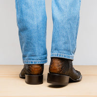 Casual outdoor scene featuring Missouri Lisboa python cowboy boots worn with jeans, focusing on unique leather texture.