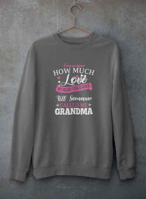 Close-up of gray crewneck sweatshirt with printed heartfelt quote hanging against concrete background.