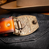 Close-up on clasp of Montana belt worn by model, showing detailed hand-stitched leather work.