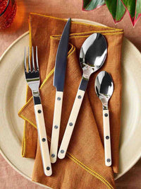 Elegant modern Nordic flatware set with ivory handles, including forks, knives, and spoons displayed on a wooden surface.
