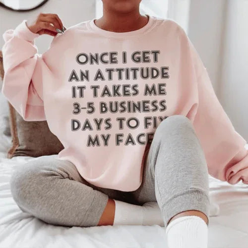 Close-up of peach sweatshirt with 'Once I Get An Attitude' text in white across front.