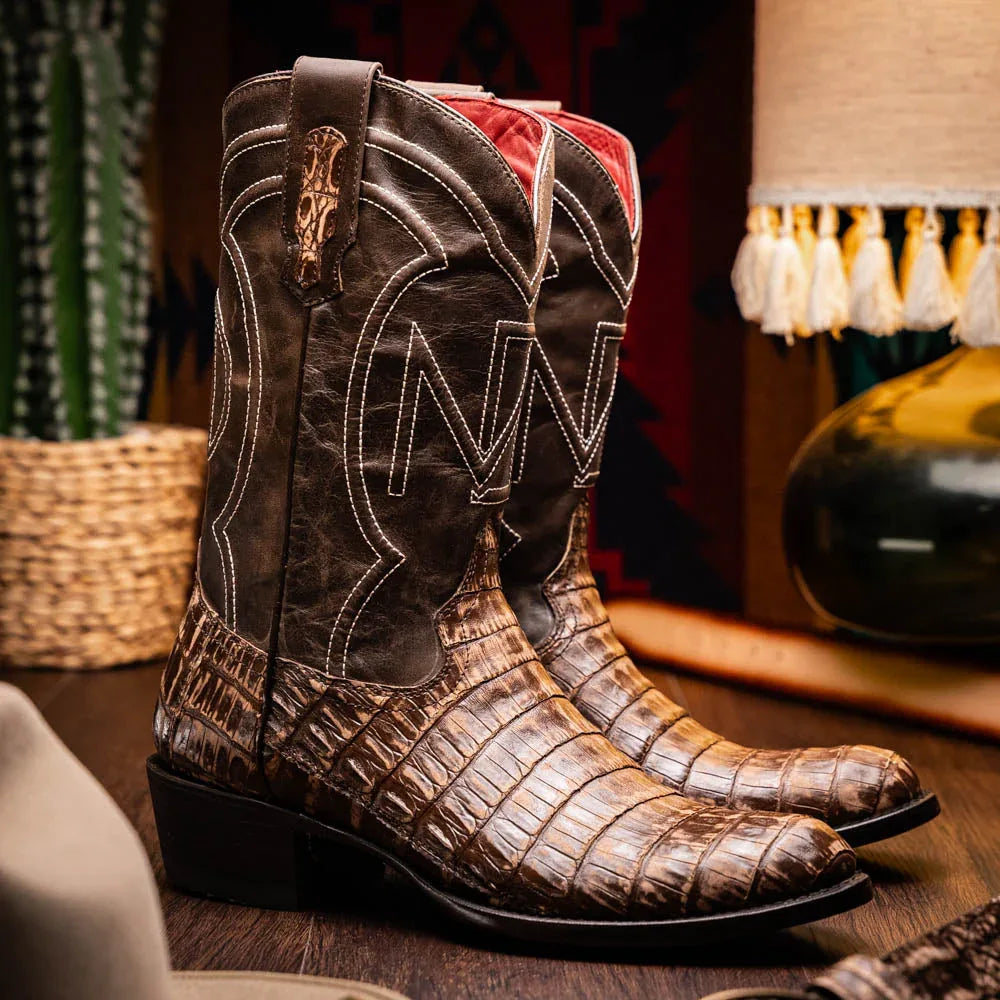 Lifestyle image of Phoenix Stone Brown cowboy boot worn with jeans outdoors on stone surface.