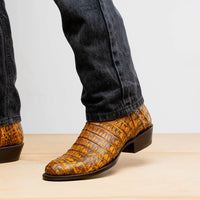 Casual outdoor scene with man wearing mustard brown caiman leather cowboy boots on gravel.