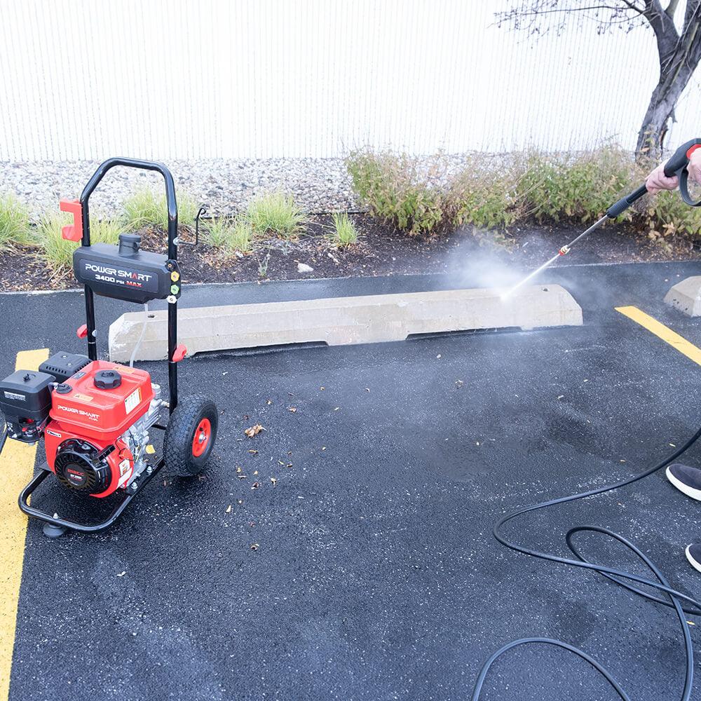 Pressure washer displayed on gray surface with hose and spray gun attached.