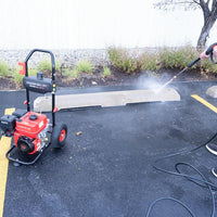 Pressure washer displayed on gray surface with hose and spray gun attached.