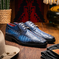 Man walking on city street wearing Ragusa stained navy caiman leather derby shoes with blue jeans.