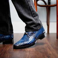 Ragusa navy caiman derby shoes worn with beige pants on urban sidewalk.